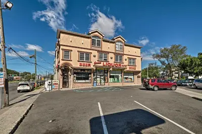 a building on a street with cars parked in a parking lot at Modern Elizabeth Apt by Dining and NYC Transit! in Elizabeth