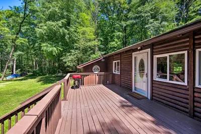 a large wooden deck on a cabin with trees at Hike, Hunt and Unwind Cozy Cabin Near Hersheypark in Jonestown
