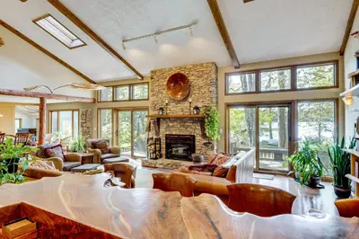 a living room with a stone fireplace and leather furniture at Luxe Poconos Pines Home with Beach and Amenities! in Pocono Pines