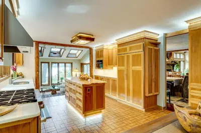 a kitchen with wooden cabinets and a stove top oven at Luxe Poconos Pines Home with Beach and Amenities! in Pocono Pines