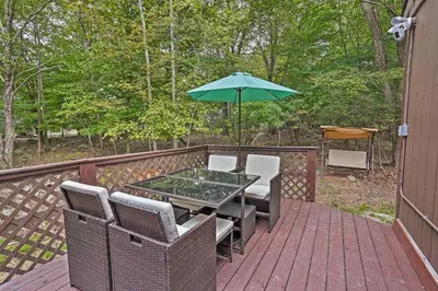 a table and chairs on a deck with an umbrella at 15 Mi to Camelback Ski Resort Home with Deck! in Tobyhanna