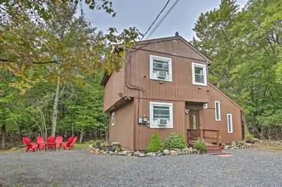 a house with red chairs in front of it at 15 Mi to Camelback Ski Resort Home with Deck! in Tobyhanna