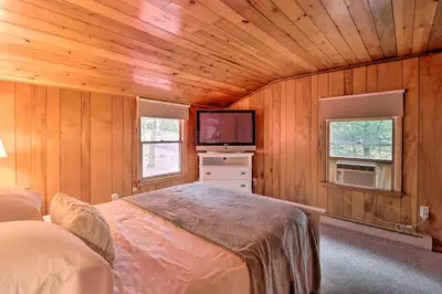 a bedroom with a bed and a flat screen tv at Deck and Fire Pit Cozy Pocono Mountain Home in Lake Harmony