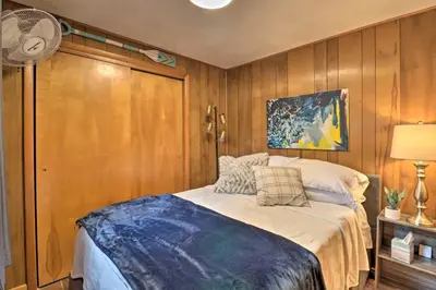 a bedroom with a bed and a fan and wooden walls at Deck and Fire Pit Cozy Pocono Mountain Home in Lake Harmony
