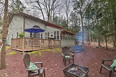 a cabin with chairs and an umbrella and a fire place at Deck and Fire Pit Cozy Pocono Mountain Home in Lake Harmony