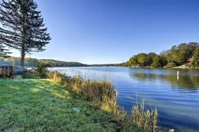 a view of a lake with a tree and grass at half Mi to Hideout Ski Lake Ariel Resort Home! in Lake Ariel