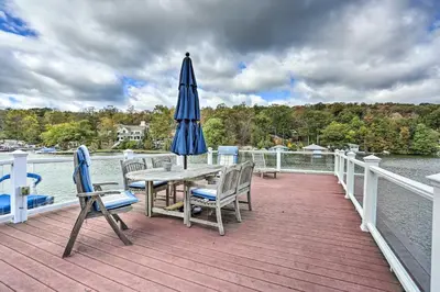 a wooden deck with a table and an umbrella and chairs at Lake Hopatcong Family Home with Boat Slip and Dock in Hopatcong
