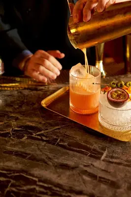 a person pouring sauce into a cup on a table at Le Meridien New York, Central Park in New York