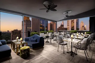 a rooftop patio with tables and chairs and a view of the city at Le Meridien New York, Central Park in New York