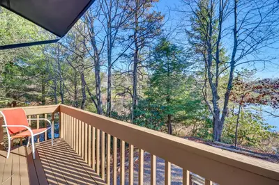 a wooden balcony with a chair and trees at Near Skiing Lakefront Gem with Kayaks in Long Pond in Long Pond