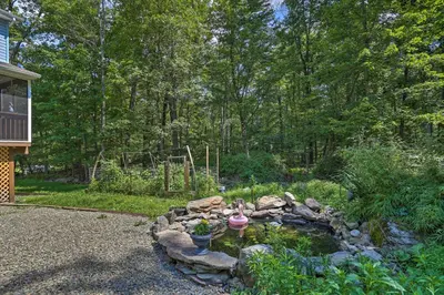 a garden with a pond with a bird bath in it at 5 Mi to Camelback Henryville Home with Hot Tub! in Henryville