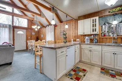 a kitchen with white cabinets and a dining room at Fire Pit and Community Perks Gouldsboro Cabin! in Gouldsboro
