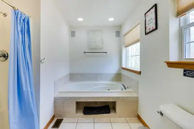 a white bathroom with a tub and a window at Deck, Game Room and Fire Pit Poconos Retreat in Albrightsville