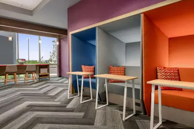 a waiting room with orange and purple walls and tables at Tru By Hilton Easton in Easton