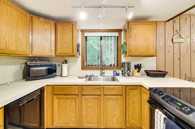 a kitchen with wooden cabinets and a sink at Fire Pit and Games! Secluded Chalet 30 Mi to Montage in Lake Ariel