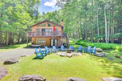 a cabin in the woods with blue chairs on the lawn at Secluded Family Cabin with Fire Pit in Lake Ariel! in Lake Ariel