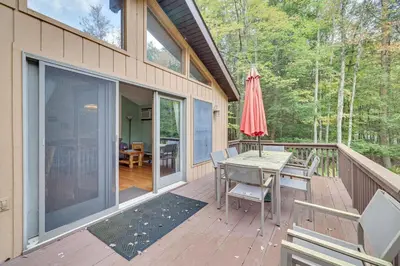a deck with a table and chairs and an umbrella at Secluded Family Cabin with Fire Pit in Lake Ariel! in Lake Ariel