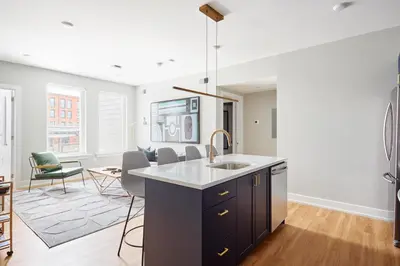 a kitchen with a sink and a living room at StayCozy at The Frankford in Philadelphia