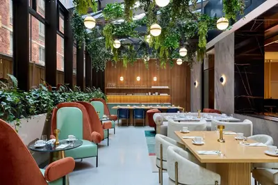 a restaurant with tables and chairs and plants at Delta Hotels by Marriott New York Times Square in New York