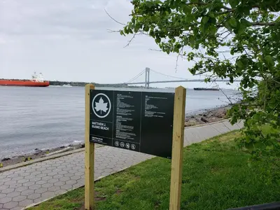 a sign in the grass next to a body of water at Harbor House Bed and Breakfast in Staten Island
