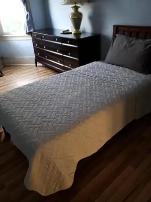 a bed in a room with a dresser and a bed sidx sidx at Harbor House Bed and Breakfast in Staten Island