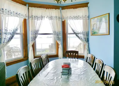 a dining room with a table and chairs and windows at Harbor House Bed and Breakfast in Staten Island