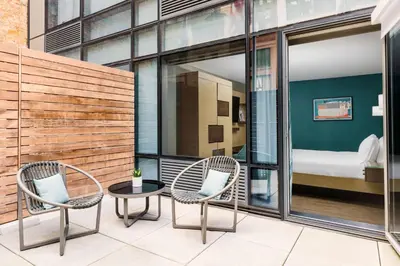 two chairs and a table on a balcony with a bedroom at Hilton Garden Inn New York Times Square North in New York