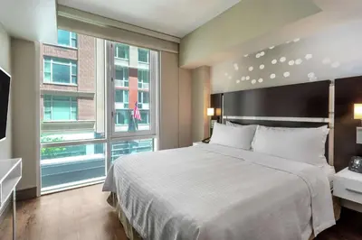 a bedroom with a large bed and a large window at Homewood Suites Midtown Manhattan Times Square South in New York