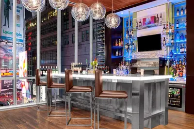 a bar with chairs and a television in a room at Hilton Garden Inn New York - Times Square Central in New York