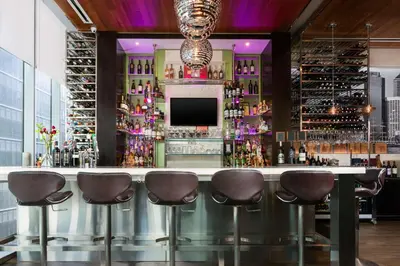 a bar with stools in a room with wine bottles at Hilton Garden Inn New York - Times Square Central in New York