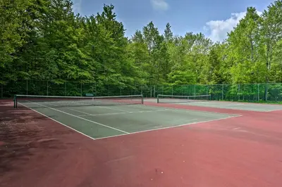 a tennis court with two tennis rackets on it at Resort Amenities and Game Room Arrowhead Lake Home! in Pocono Lake