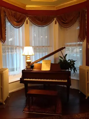 a piano sitting in front of a window with a lamp at Gifford-Risley House Bed and Breakfast in Media