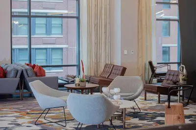 a living room with chairs and tables and windows at Canopy By Hilton Jersey City Arts District in Jersey City