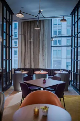 a restaurant with tables and chairs and large windows at Canopy By Hilton Jersey City Arts District in Jersey City