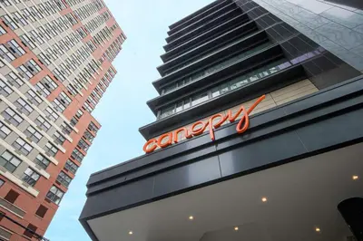 a sign on the side of a building with two tall buildings at Canopy By Hilton Jersey City Arts District in Jersey City