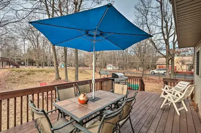 a table with a blue umbrella on a deck at Walk to Pool and Lake Albrightsville Vacation Home! in Albrightsville