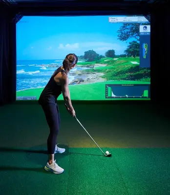 a woman playing golf in front of a screen at Fitler Club in Philadelphia