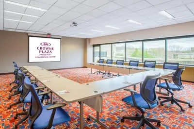 a conference room with tables and chairs and a projection screen at Crowne Plaza Princeton - Conference Center by IHG in Princeton