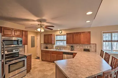 a kitchen with wooden cabinets and a ceiling fan at 6 Mi to Skiing Family Poconos Home w Decks! in Albrightsville