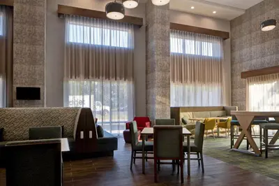 a waiting room with tables and chairs and windows at Hampton Inn & Suites Deptford, Nj in Deptford