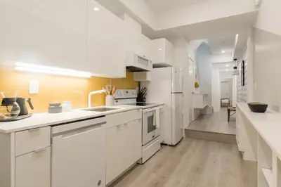 a white kitchen with white appliances and a hallway at Abode XS House Stunning Architectural Flat in Philadelphia