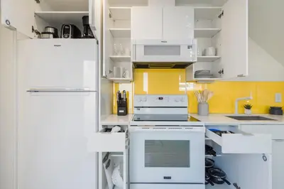 a kitchen with white appliances and yellow walls at Abode XS House Stunning Architectural Flat in Philadelphia