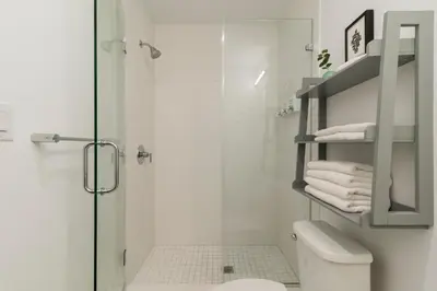 a white bathroom with a shower and a toilet at Abode XS House Stunning Architectural Flat in Philadelphia