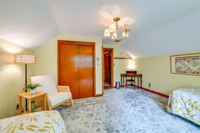 a bedroom with a bed and a chair and a chandelier at Serene Home with On-Site Brook in Callicoon Center in Callicoon Center