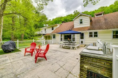a patio with two red chairs and a table at Serene Home with On-Site Brook in Callicoon Center in Callicoon Center