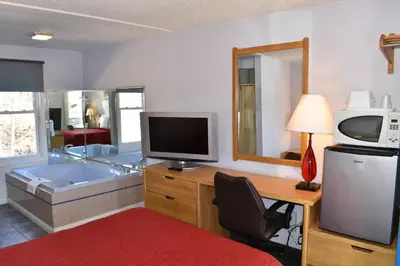 a room with a tub and a desk with a television at POCONO NIGHT LODGE in Bartonsville