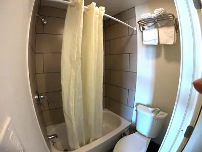 a bathroom with a white shower curtain and a toilet at Rest Inn - Elizabeth in Elizabeth