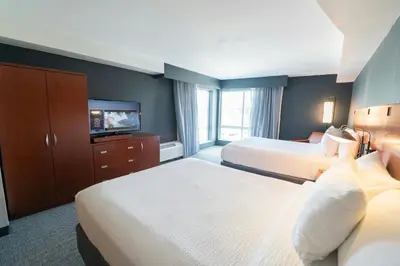 a hotel room with two beds and a flat screen tv at Courtyard by Marriott Philadelphia Springfield in Springfield