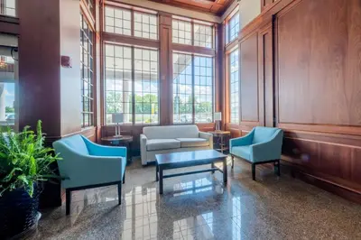 a living room with chairs and a table and windows at HomeTowne Studios by Red Roof Wilmington - New Castle in New Castle