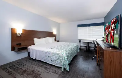 a hotel room with a bed and a desk and a television at HomeTowne Studios by Red Roof Wilmington - New Castle in New Castle